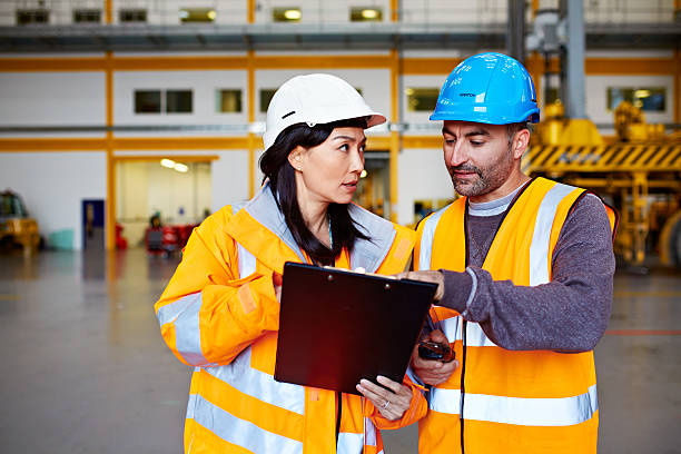 Shot of two warehouse workers talking together over a clipboard